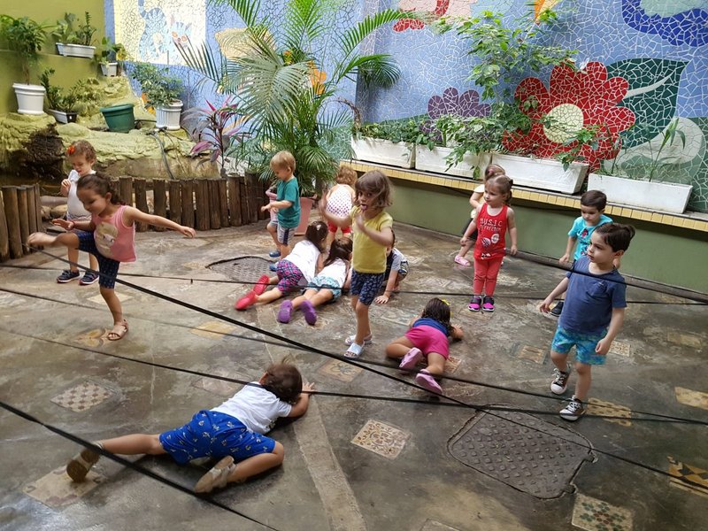 Crianças brincando no pátio com mural de mosaico da Criançartes